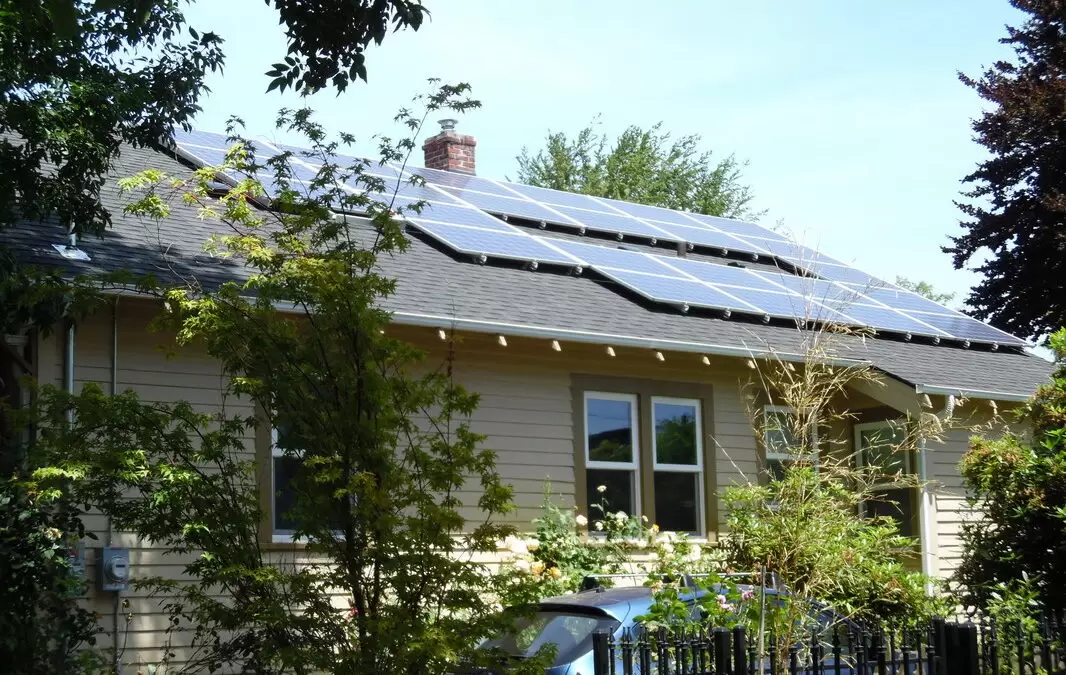 My Solar Story: Leif Rhoades 6 House with solar panels installed on the roof, surrounded by greenery and trees.