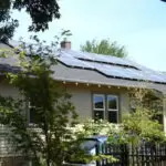My Solar Story: Leif Rhoades 4 House with solar panels installed on the roof, surrounded by greenery and trees.