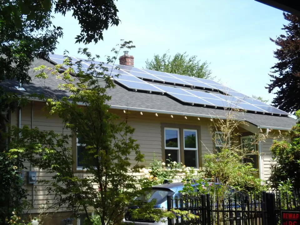 My Solar Story: Leif Rhoades 10 House with solar panels installed on the roof, surrounded by greenery and trees.
