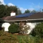 Residential Dwelling 1 Residential dwelling with white exterior walls and a roof fitted with solar panels; surrounding garden and greenery in the yard