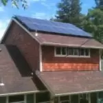 Residential Dwelling 2 1 Residential dwelling with brick exterior and roof-mounted solar panels; sloped roof, skylight, and surrounding trees visible
