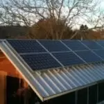 Residential Dwelling 5 1 Residential dwelling roof features an array of solar panels mounted on a metal roof, capturing sunlight for an on-site solar energy system.