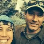 My Solar Story: Brion Wickstrom 4 Brion and Sarah posing together with a waterfall in the background, both wearing outdoor clothing and hats.