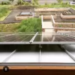 Solar Incentives can Reduce Your Tax Burden and help you go Green!!! 4 Solar panels positioned on a roof with a view of a garden area and planting beds in the background.